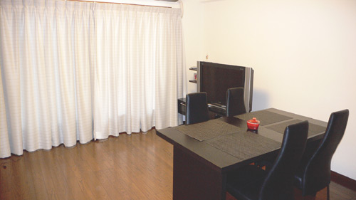 ほぼ正方形に近い形が広さを感じさせるLDK。ダイ二ングセットのデザインがシックな雰囲気を作り出している