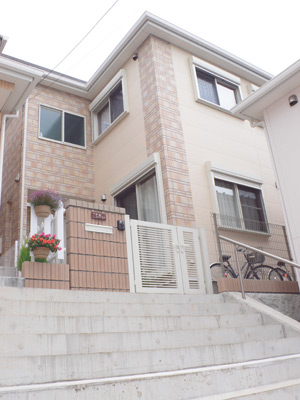 10段ほどの階段の上に建つ甲地さんのご新居。クリーム色とレンガ風のサイディングが優しい印象