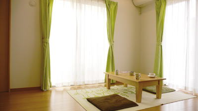 南と西に大きな窓のあるリビング。フローリングの色やインテリアに暖かみが感じられる