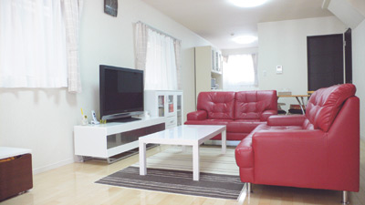 赤いソファーがポップな雰囲気を作り出すリビングは、窓も多くとても明るい