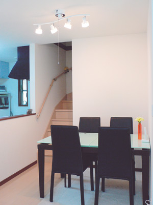 リビング内に階段があり人の出入りがすぐ分かる。もともと付いていたダイ二ングセットにはセンス良くお花が飾られている