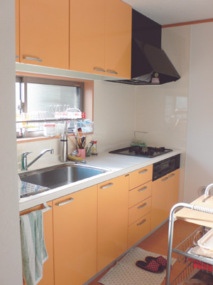 キッチンは壁付けタイプ。明るいオレンジ色が暖かい印象