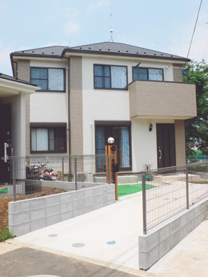 アイボリーと深いベージュの2色使いの外壁が印象的な佐々木さんのご新居。手前には2台分の駐車スペースがある