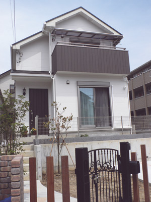 白い外壁に扉とバルコニーの色がアクセントになっている高田さんのマイホーム