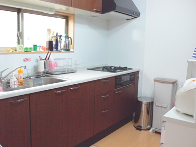 ダークブラウンの木目が落ち着いた印象のキッチンは、シンクの正面に窓があり明るい