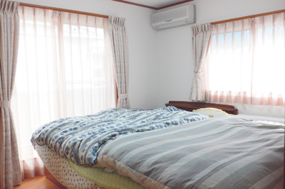 バルコニーに続く掃き出し窓を含む2つの窓がある明るい部屋がご家族全員の寝室